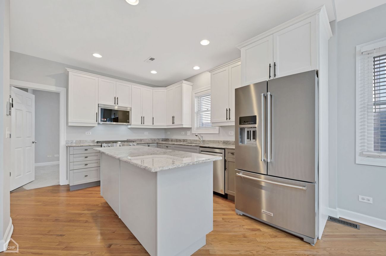 Damen Ave Condo — kitchen with white cabinetry and stainless appliances