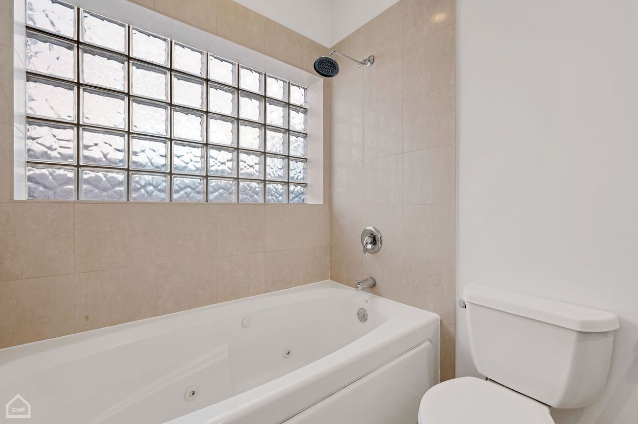Damen Ave Condo — primary bathroom whirlpool tub with glass block window