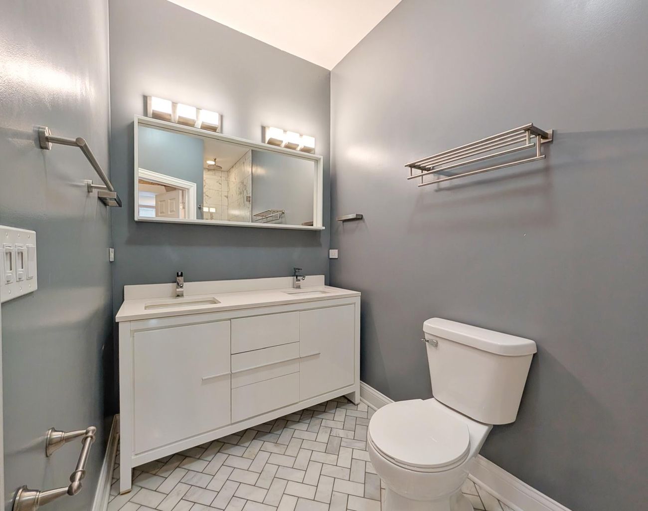 The Evergreen — bathroom in the third unit with white double vanity and herringbone tile floor