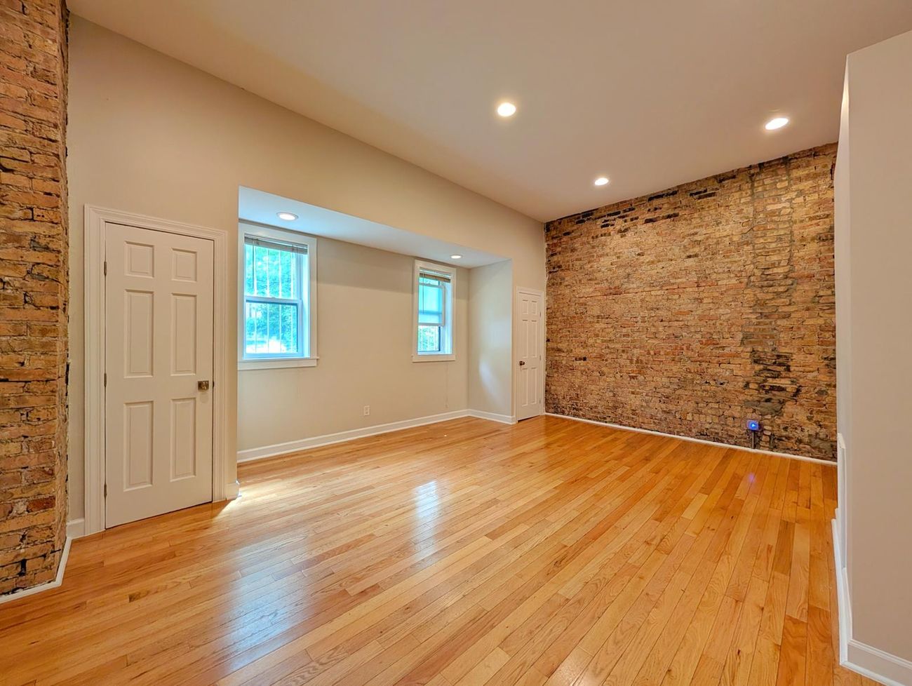 The Evergreen — living room in the third unit with an exposed brick accent wall